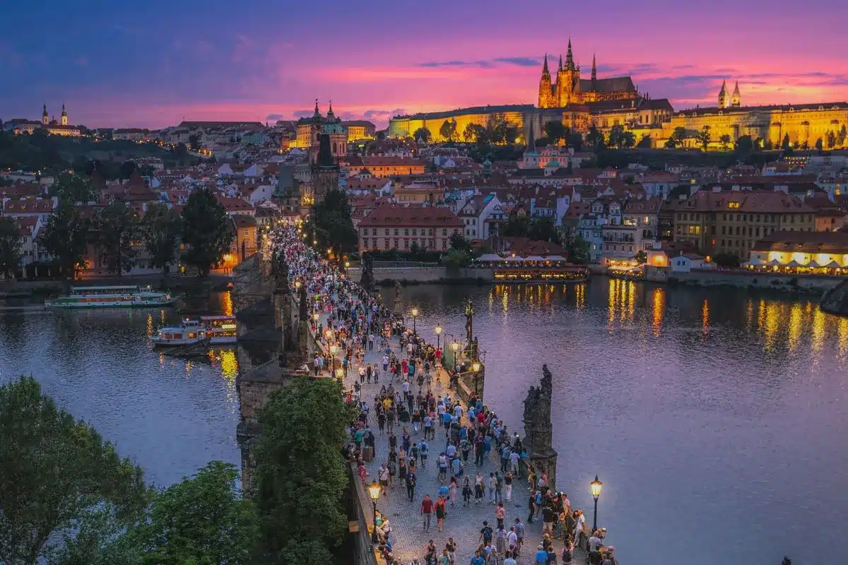 Travelers crossing Charles Bridge in Prague at sunset – stay connected in Europe with Orange Travel eSIM
