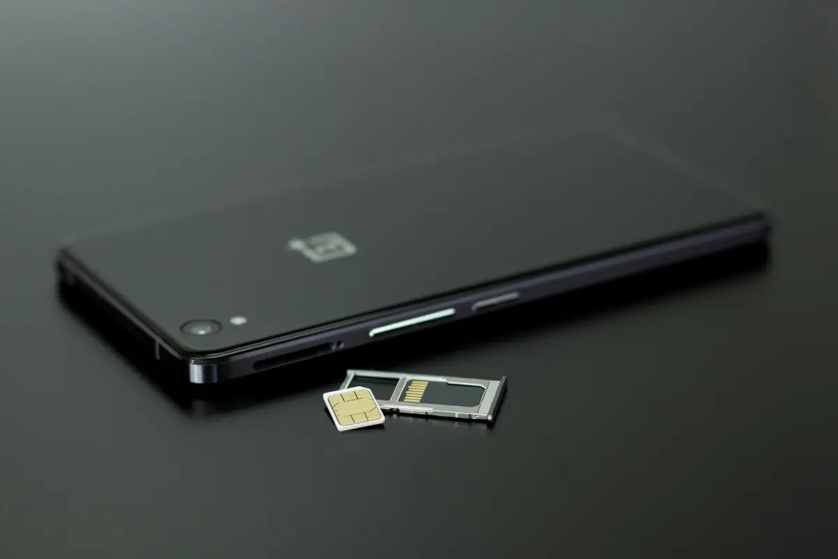 Smartphone with physical SIM card and SIM tray on dark background – eSIM vs physical SIM comparison