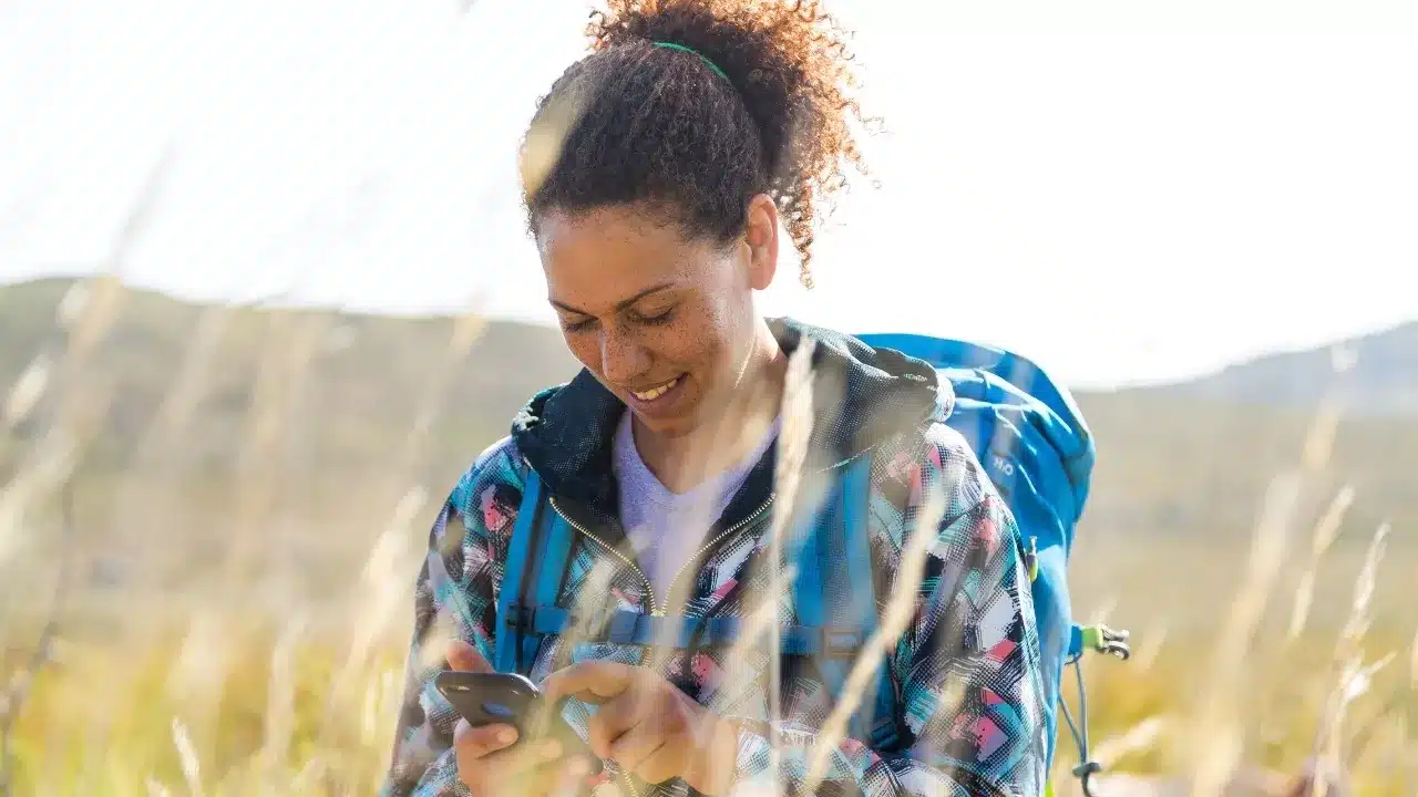 a woman holding her phone standing in a field