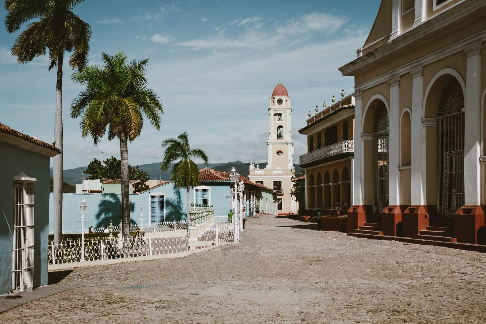 Colonial Plaza Mayor of Trinidad, Cuba with palm trees and a bell tower under a blue sky