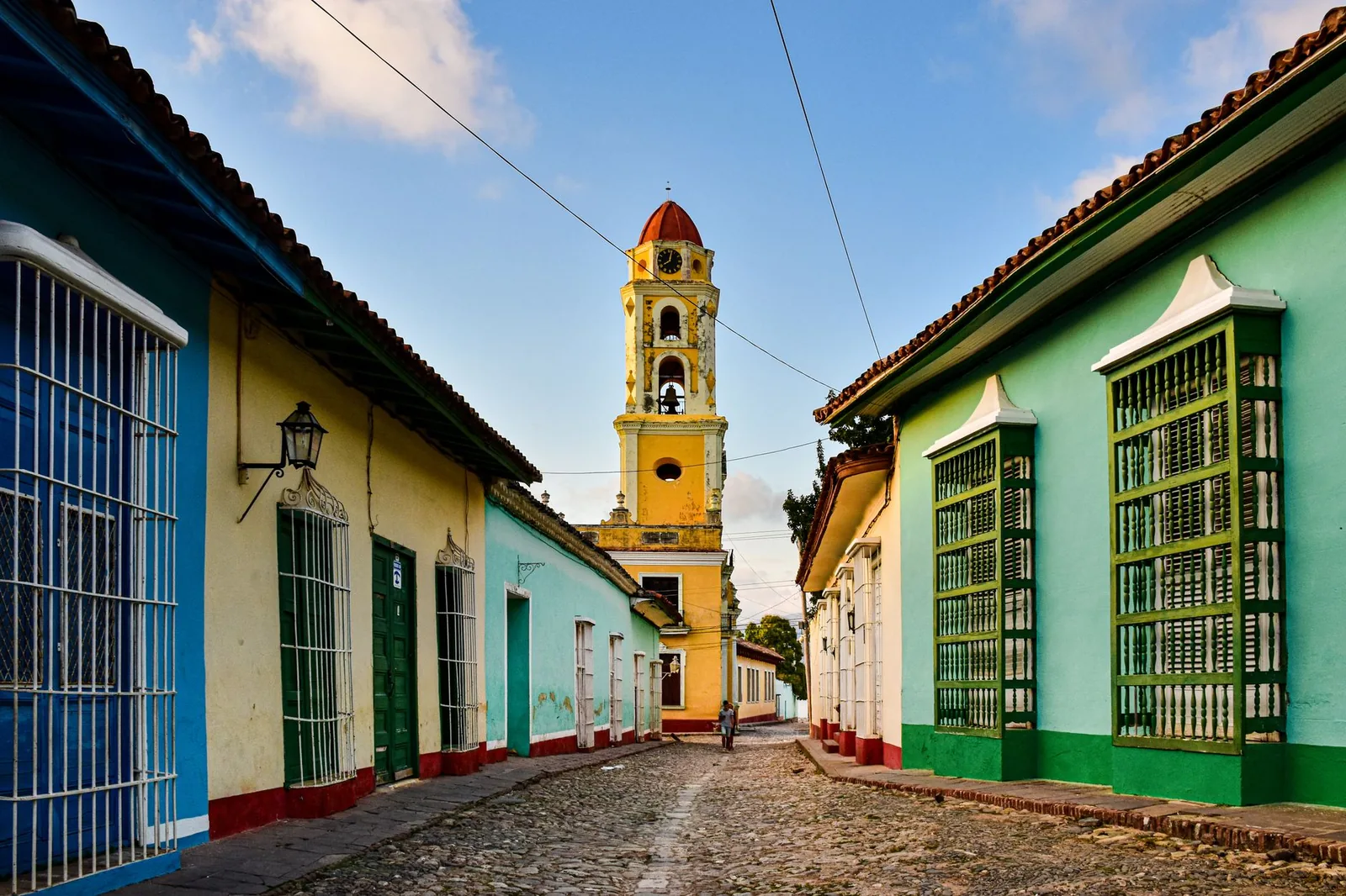 Cobblestone street in Trinidad, Cuba with colorful colonial houses and the yellow bell tower of the San Francisco convent