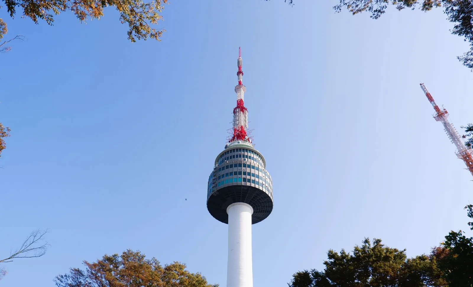 Namsan N Seoul Tower rising into a clear blue sky, framed by autumn foliage in Seoul, South Korea