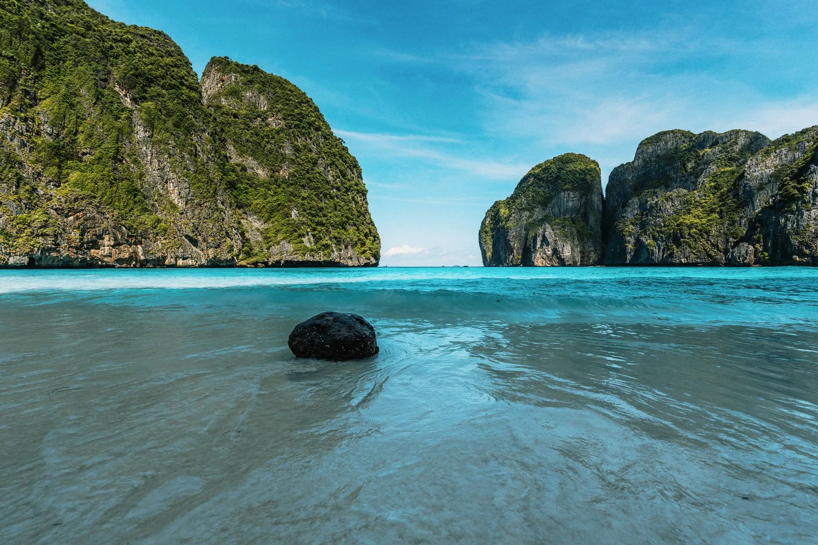 Maya Bay in the Phi Phi Islands of Thailand, crystal-clear turquoise waters framed by lush limestone cliffs