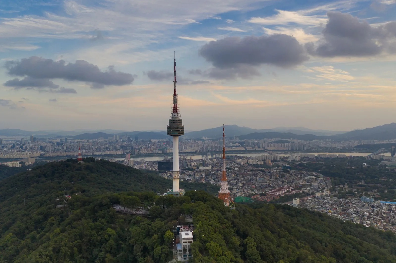 Aerial view of Namsan N Seoul Tower rising above the vast Seoul cityscape at sunset