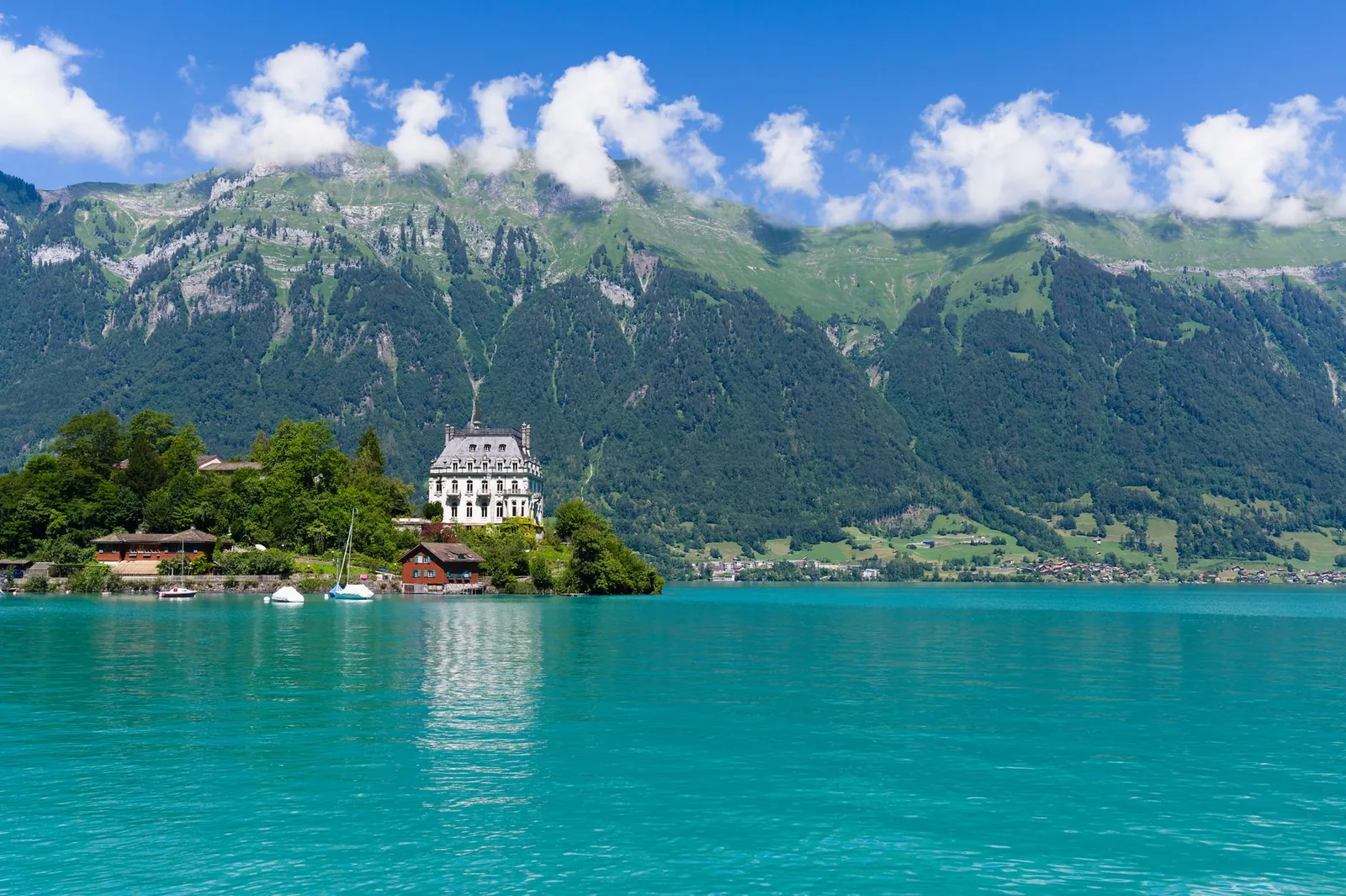 The turquoise waters of Lake Brienz with the village of Iseltwald and green alpine slopes, Switzerland
