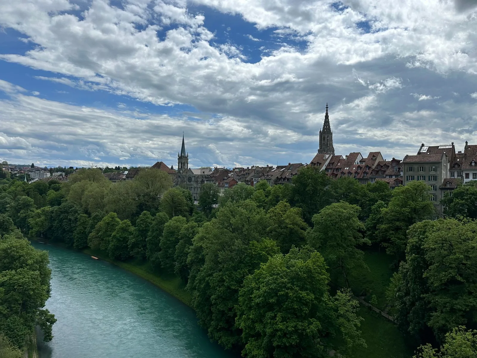 The old town of Bern beside the turquoise Aare river with the cathedral spire and historic rooftops, Switzerland
