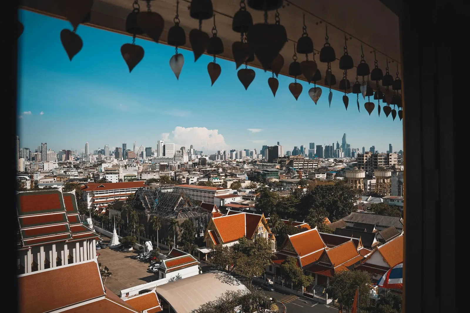 View of the Bangkok skyline with the rooftops of traditional Thai temples in the foreground under a clear sky