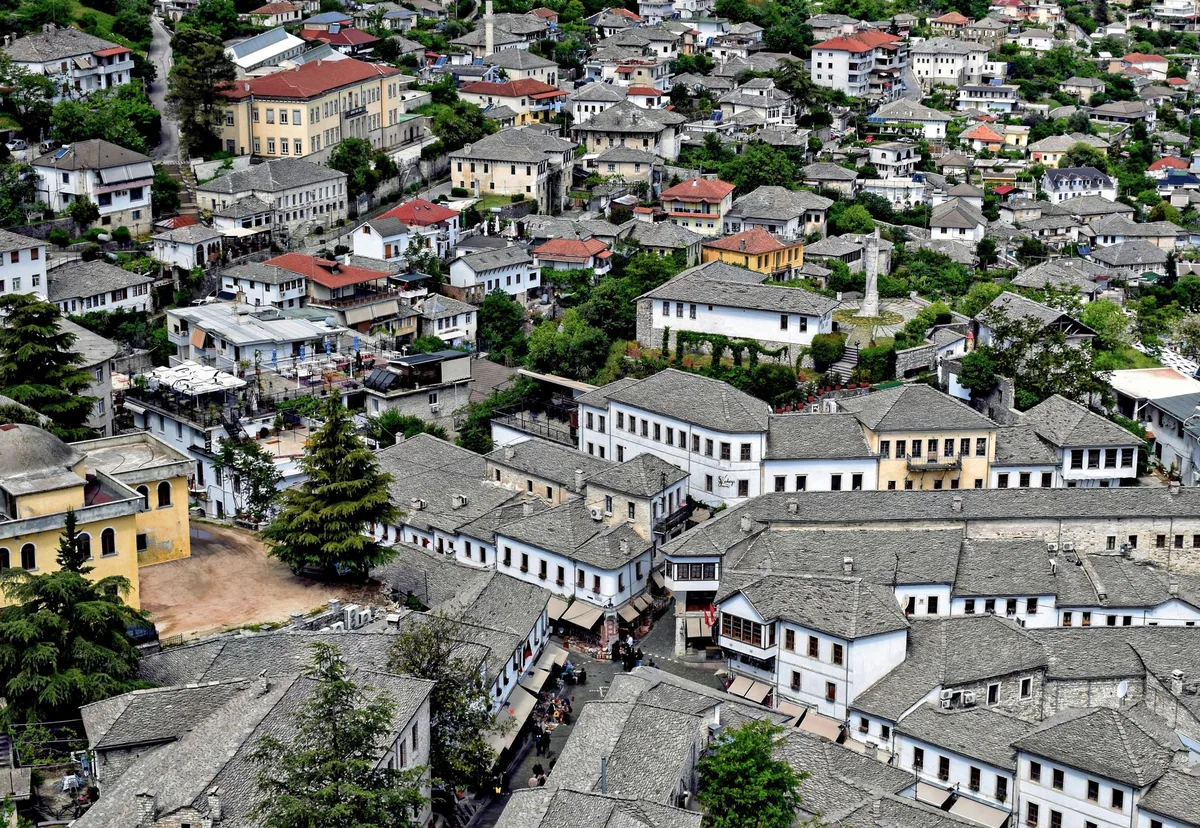 Cobbled old-town street of Gjirokastër with stone Ottoman houses and a hilltop castle in Albania