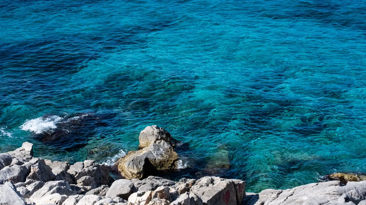 Turquoise sea and pebble beach of the Albanian Riviera near Ksamil under a clear summer sky