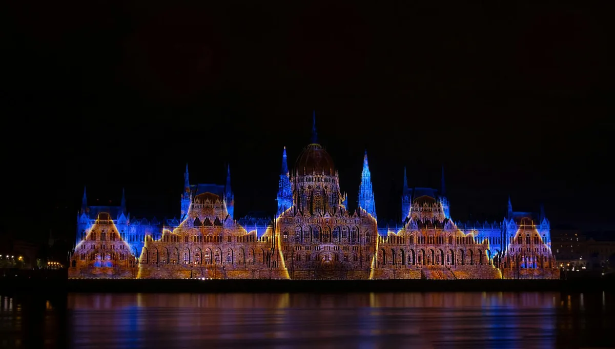 The Hungarian Parliament in Budapest lit up at night beside the Danube, with the Chain Bridge in the background