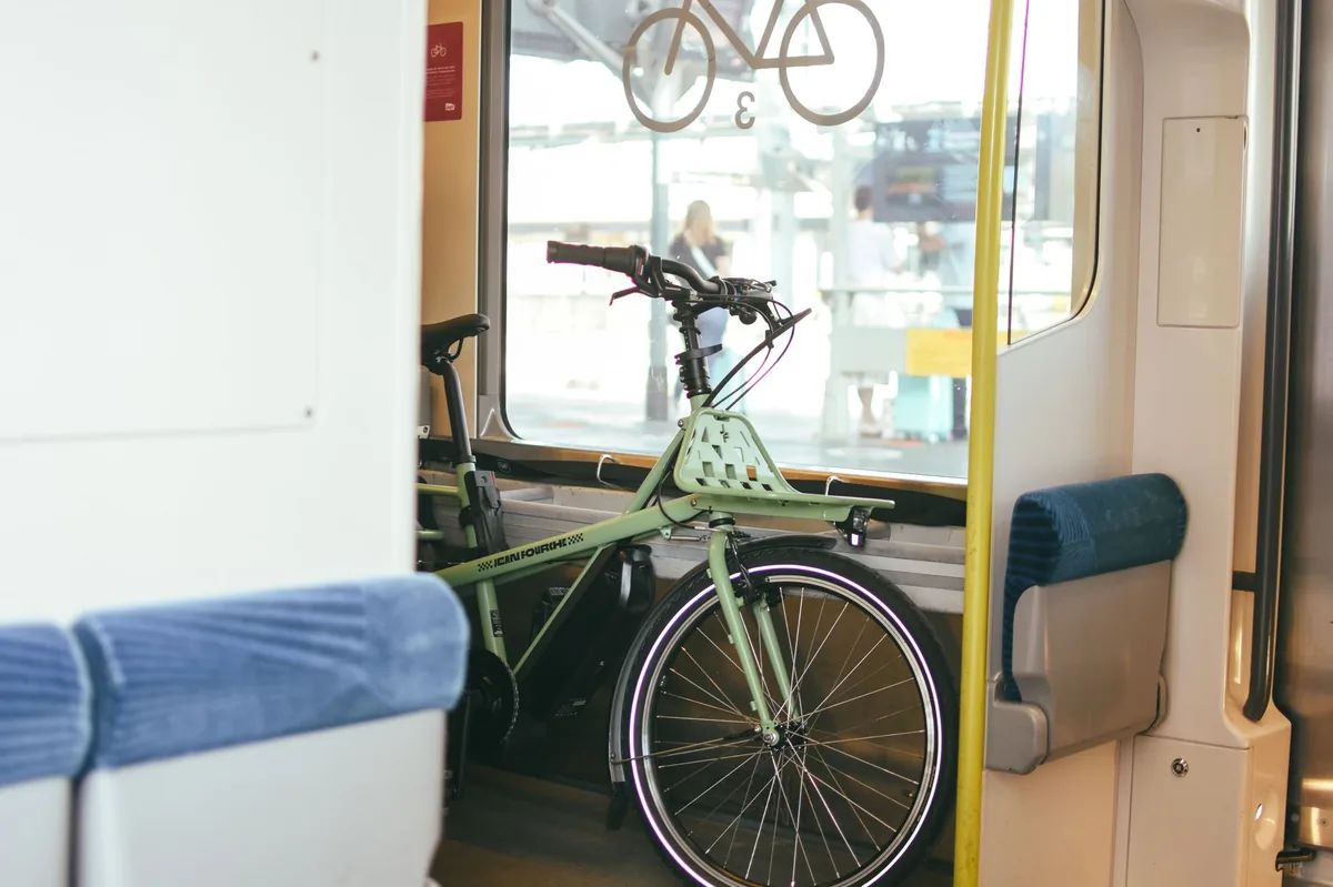 Loaded touring bike with panniers on a railway platform in Europe, beside a regional train with a bike carriage