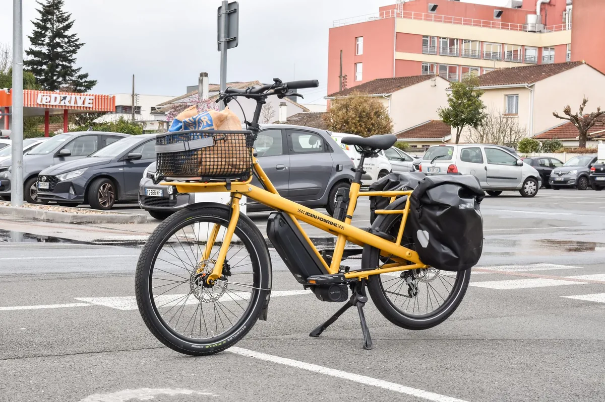 Bicicleta de viaje cargada con alforjas apoyada en el andén de una estación europea, junto a un tren regional con espacio para bicis
