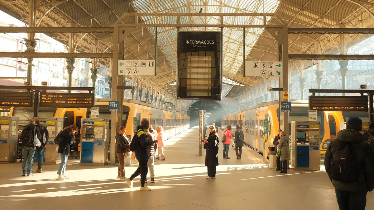Traveller on a European station platform checking a train ticket app on a smartphone, a modern train standing at the platform