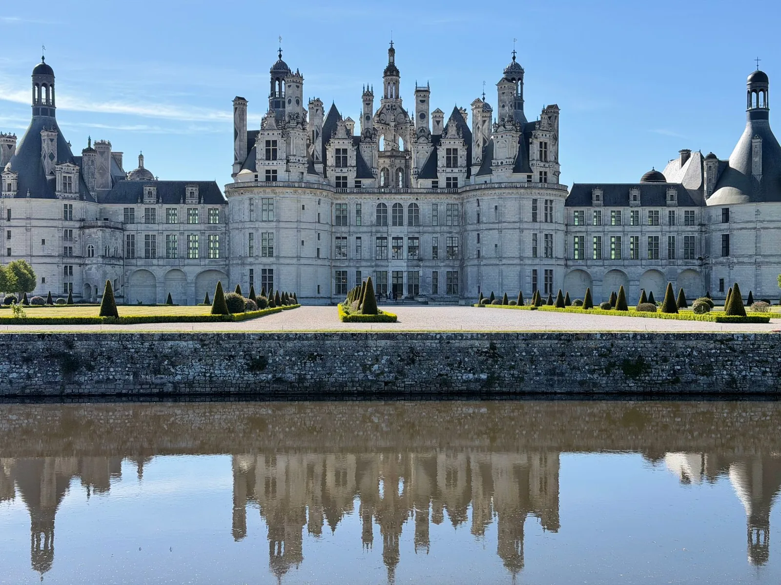 The Chateau de Chambord and its Renaissance turrets mirrored in the calm canal, in the Loire Valley