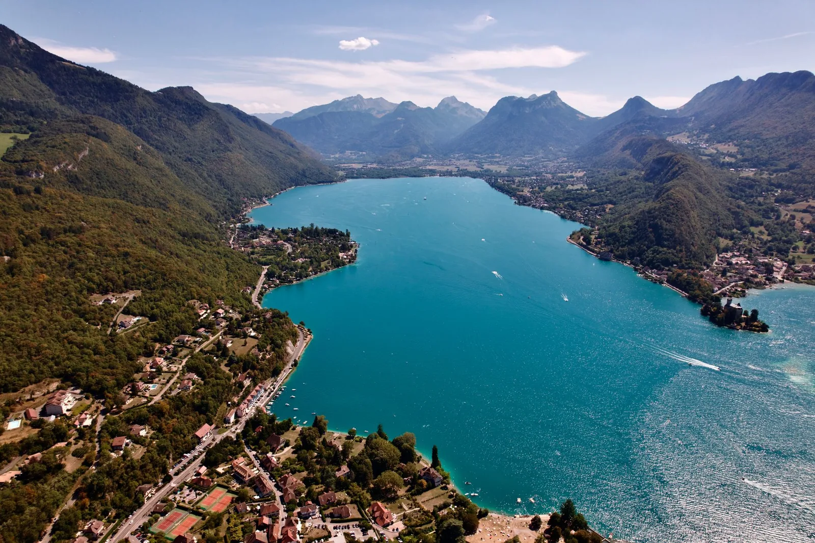 Vista aerea del lago de Annecy de aguas turquesas, rodeado de montanas verdes en los Alpes