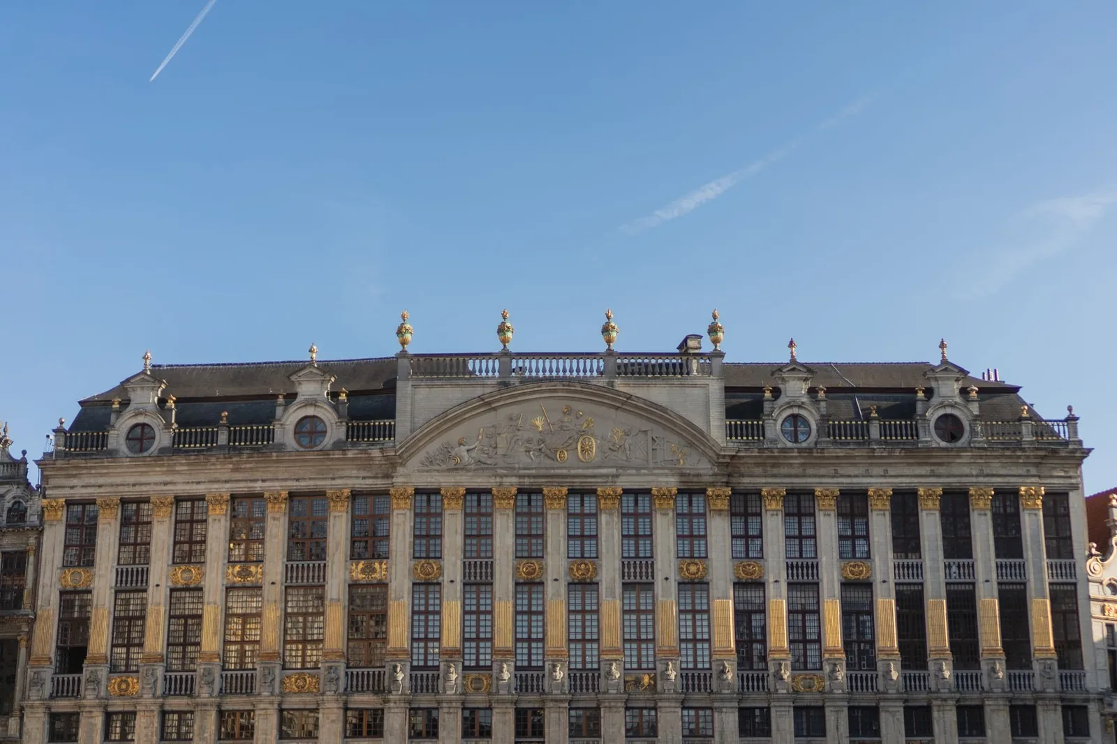 Fachada barroca dorada de una casa gremial de la Grand-Place de Bruselas, con sus adornos y estatuas recortados sobre un cielo azul