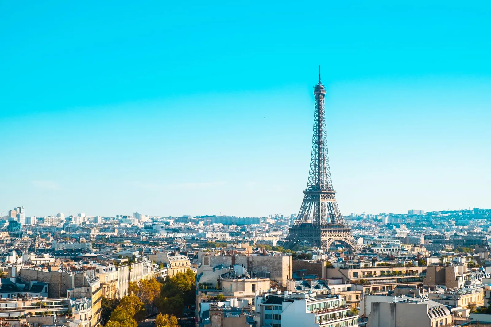 La tour Eiffel domine les toits de Paris sous un ciel bleu limpide, panorama sur la capitale